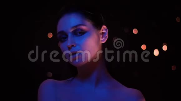 美丽的女性特写镜头带着紫罗兰色的霓虹灯和bokeh背景看着相机视频的预览图