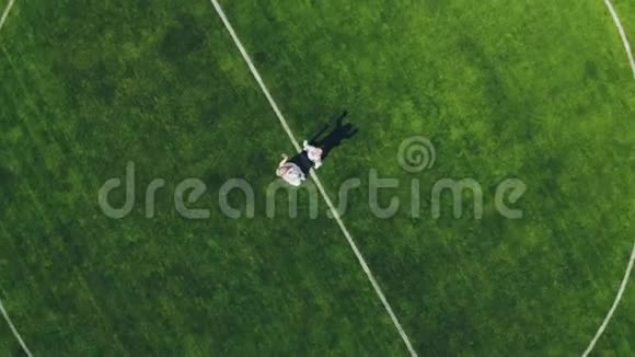 空中视频从顶部观看在体育场在一个绿色足球场的中心新婚夫妇着婚纱视频的预览图