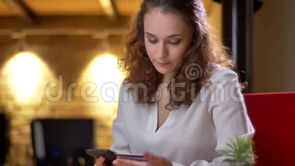 年轻卷发女商人用心使用信用卡和智能手机进行交易的肖像视频的预览图