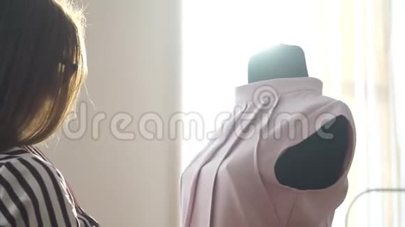 一个穿着夹克的模特站在一个光线充足的房间里女裁缝站在他们的工作旁边做标记视频的预览图