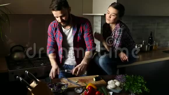 漂亮的年轻夫妇在家厨房做饭时吃健康的食物人浇沙拉油和盐女人吻男人情景视频的预览图
