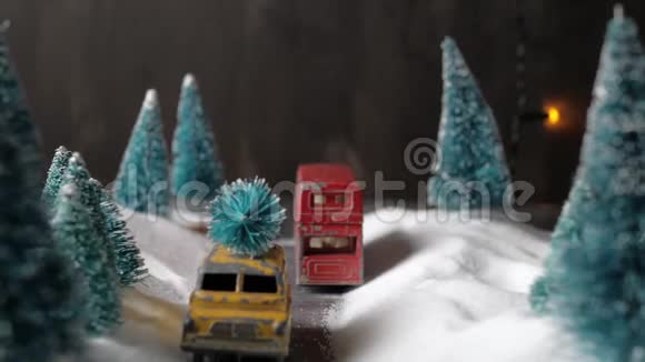 冬天的森林缩影有一辆黄色的小玩具车屋顶上有一棵圣诞树双层红色巴士雪堆视频的预览图