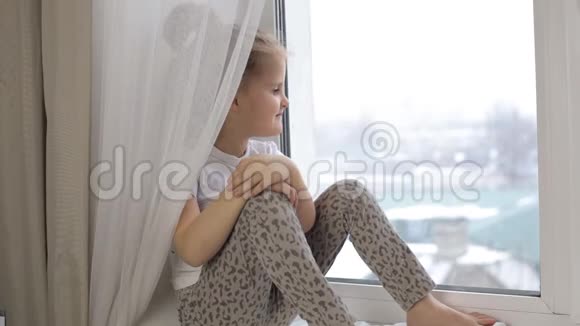 一个小女孩坐在窗台上看着窗外视频的预览图