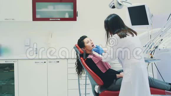 病人坐在牙科椅上在这段时间里医生和她交流他们一起微笑这就是视频的预览图