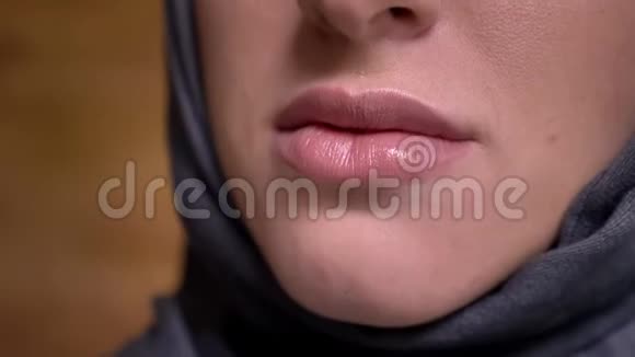 在布里克肯墙背景上穆斯林妇女戴着头巾微笑成镜头的特写唇画像视频的预览图