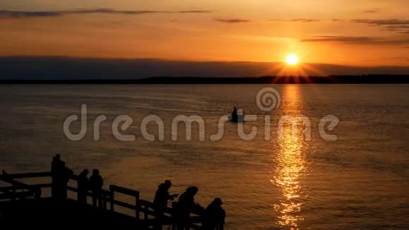 美丽的日出阳光照耀着湖面人们钓鱼的轮廓视频的预览图