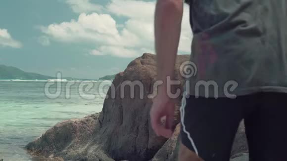 塞舌尔普拉斯林岛一群面目全非的人在海里的石头上行走美丽的海景蓝色洁净水视频的预览图