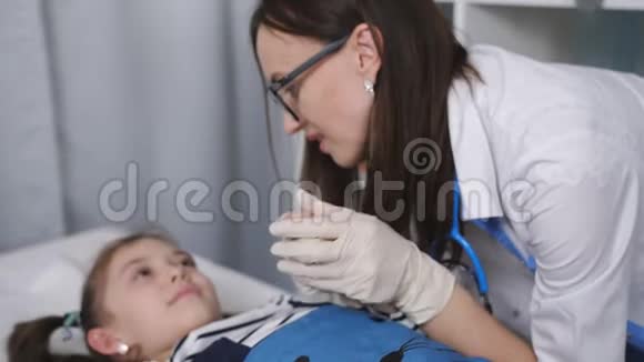 微笑友好的女医生与躺在医院病床上的儿科医生办公室里的小病人交谈视频的预览图