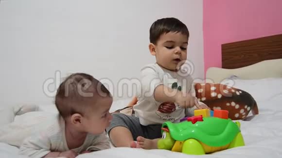 幼儿和2个月大的宝宝一起躺在床上幼儿玩教育玩具乌龟宝宝在旁边转视频的预览图