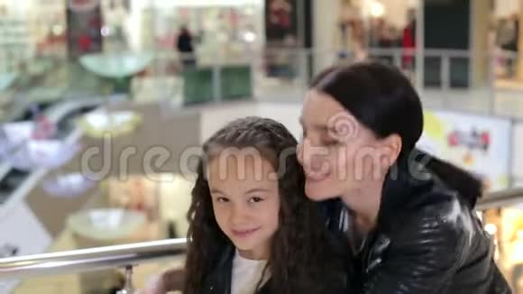 快乐的妈妈穿着皮夹克在一个大型购物中心拥抱她的女儿视频的预览图