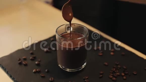 一个热巧克力的特写镜头从勺子掉进一个装满玻璃的杯子里视频的预览图