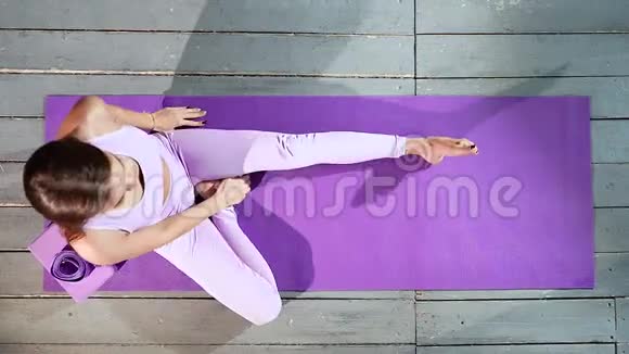 年轻迷人的女人在瑜伽垫上做伸展运动上景视频的预览图