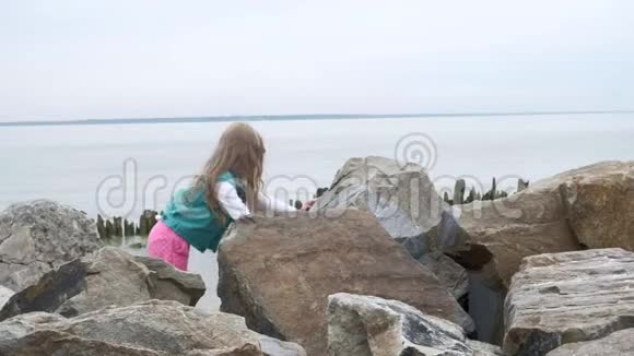 女孩学龄前儿童在海滨的大石头上玩耍视频的预览图