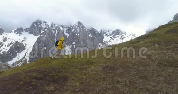 徒步旅行者在白雪皑皑的群山背景下登上一座小山视频的预览图