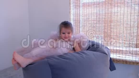 小女孩穿着一件漂亮的连衣裙坐在托儿所的椅子包里视频的预览图