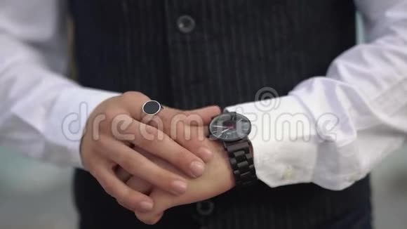 穿着古典西装的人看着他手上的手表男人手上有一枚结婚戒指注意时间视频的预览图