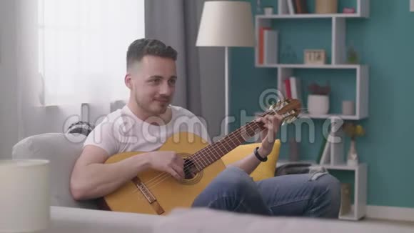 跟踪男人在一个舒适的客厅里为他的朋友弹吉他视频的预览图