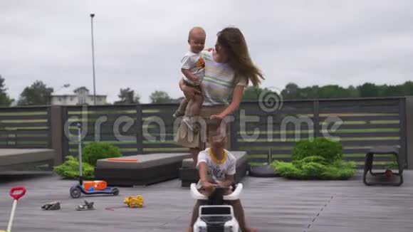 年轻的母亲在绿色的花园里和她的小男孩儿子兄弟一起玩带着汽车家庭的价值观是温暖的视频的预览图