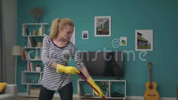 在舒适的公寓里手持的女人清洁地板跳舞视频的预览图