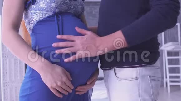 把孕妇和她的丈夫紧紧地抱在一起抚摸她的腹部生育观念怀孕家庭幸福视频的预览图