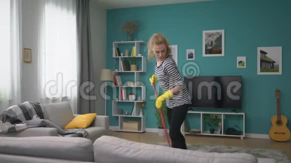 在舒适的公寓里大片的女人打扫地板跳舞视频的预览图