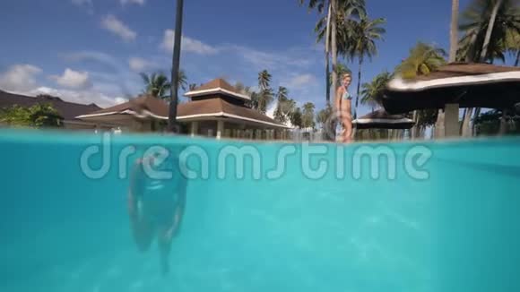 小女孩独自在热带度假胜地的蓝色游泳池游泳视频的预览图