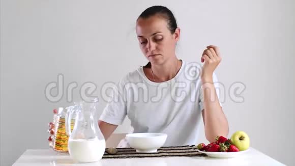 年轻女子正在吃早餐玉米片上有牛奶和水果视频的预览图