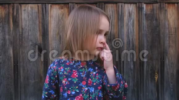 一个悲伤的小女孩在木栅栏上摆姿势的特写肖像视频的预览图