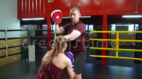 年轻女性在拳击场接受带垫的训练视频的预览图