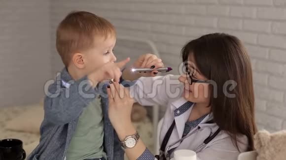 儿童医生用木铲检查一个生病的小男孩的喉咙视频的预览图