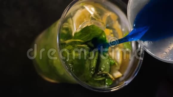 酒保把蓝色的酒倒入一个塑料杯里里面有苏打水柠檬和薄荷冷饮制作过程关门视频的预览图