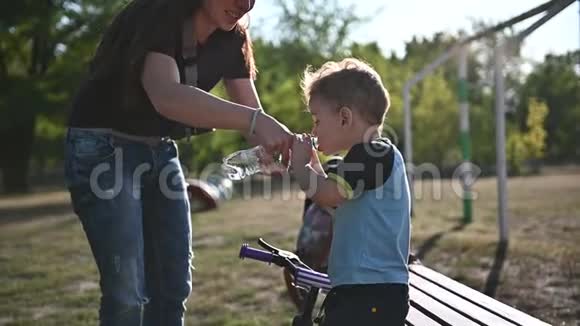 小男孩喝水坐在操场的长凳上生活方式视频没有稳定视频的预览图