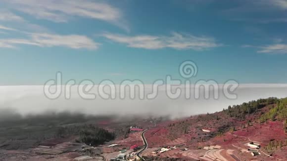 高空超脱美丽的飞行在云层上方的红色火山谷一个有白色房子和红色的小镇视频的预览图