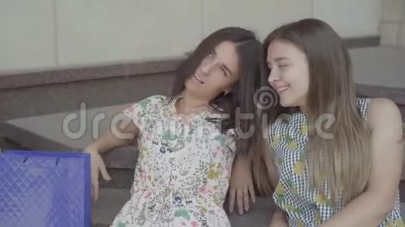 描绘两个迷人的女朋友坐在楼梯上购物后带着购物袋女士们都累了视频的预览图