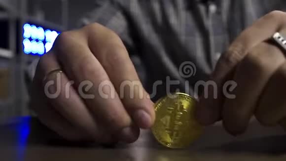 人类手正在棕色桌子上快乐地旋转着新的大金比特币硬币视频的预览图