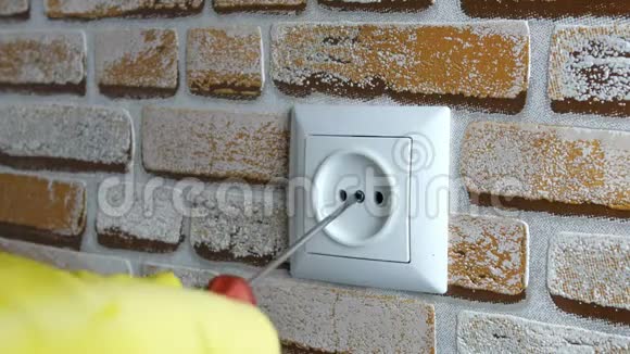 人手戴橡胶手套用螺丝刀在房子的砖墙上安装插座视频的预览图