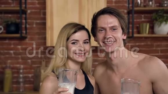 一对年轻的白种人夫妇在家里的厨房里喝健康的牛奶的肖像健康的饮料饮食健康的生活方式视频的预览图