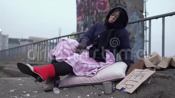 无家可归的女人欣赏穿在厚厚的红色袜子上的鞋子欣赏地看着夹克视频的预览图