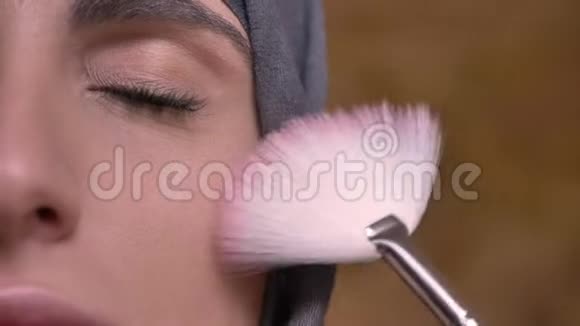 特写幻灯片拍摄的女性手做化妆使用平刷穆斯林妇女在头巾上的布里肯墙背景视频的预览图
