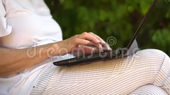 中年妇女在户外的笔记本电脑上工作微笑的中年祖母在电脑上遥远地工作视频的预览图