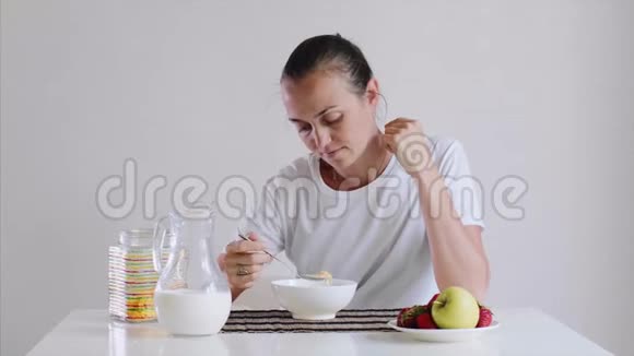 年轻的女人吃玉米片和牛奶作为早餐有食欲视频的预览图