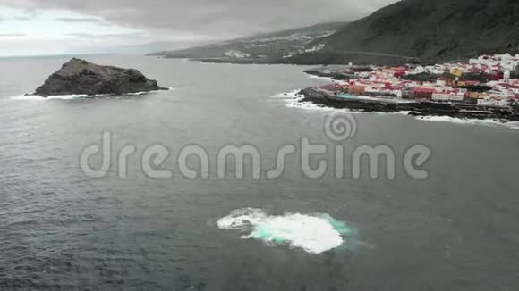 空中射击海洋水域的火山礁波浪冲击着他形成白色泡沫小镇位于视频的预览图