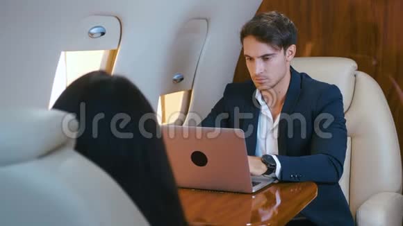 年轻的商人在私人飞机上用笔记本电脑工作成功的商业百万人头等舱旅行视频的预览图