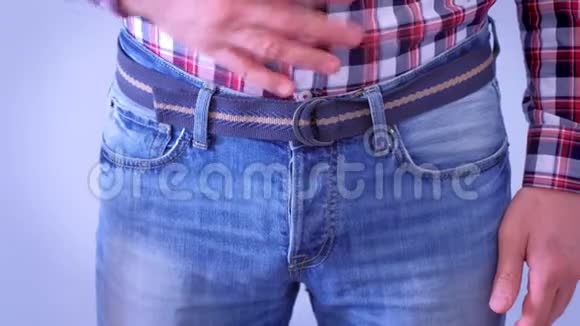 男人几乎不扣牛仔裤的腰带拉着肚子双手特写视频的预览图
