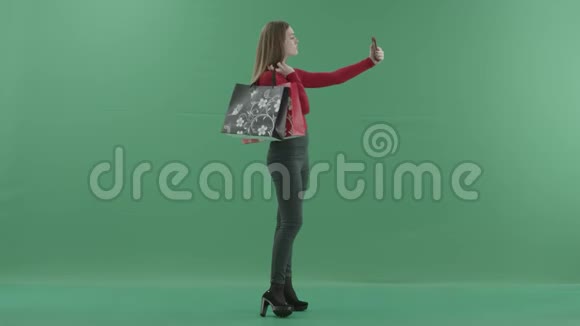 漂亮的女人穿着休闲服拿着购物袋在手机上自拍她站着视频的预览图
