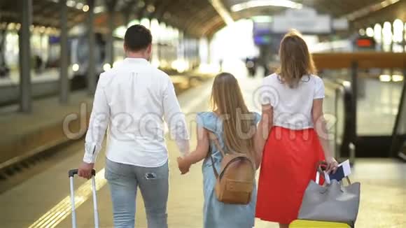年轻的家庭和可爱的女儿走在铁路站台上拿着西装最佳旅行和假期概念视频的预览图