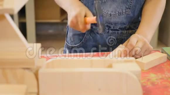 孩子们在工艺车间玩耍一个女孩锤钉子的特写镜头穿牛仔裤的可爱女孩4k视频的预览图