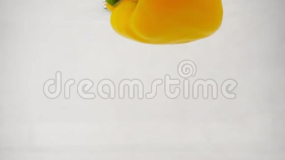 一个新鲜的黄铃状辣椒落入水中中间有飞溅和气泡视频的预览图