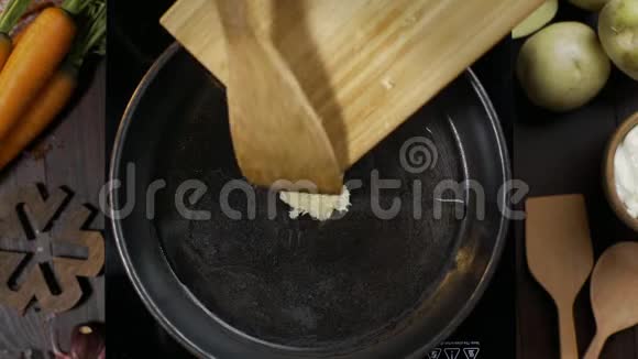 平躺视频厨师用木制厨房铲子在热锅上搅动大蒜烹饪素食桌面视频的预览图