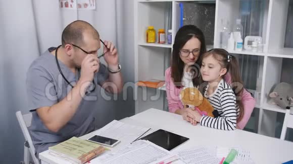 母亲带着她的小女儿在医生办公室寻求建议和一位男医生交谈视频的预览图